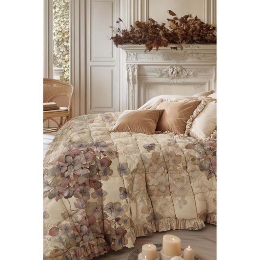 Trapunta e copriguanciali con gala Promenade su un letto romantico e accogliente, con dettagli delicati di ortensie.